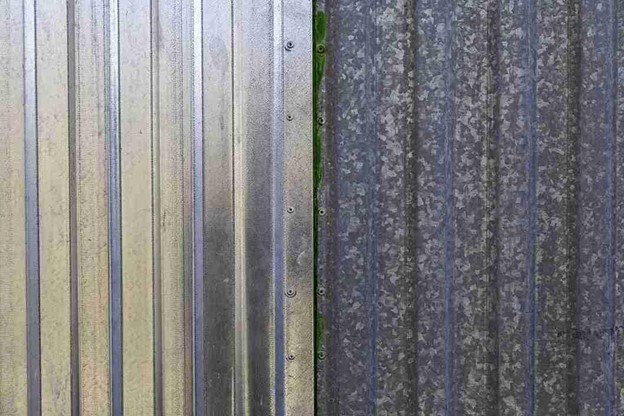Close-up of galvanized metal fence panels attached to sturdy posts, showing secure fasteners and durable construction.