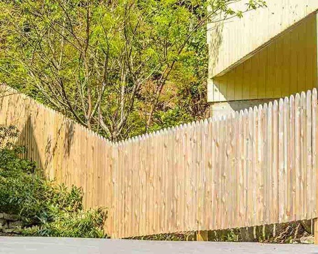 Tall cedar side-by-side privacy fence installed along a sloped residential property with clean lines and consistent board spacing.