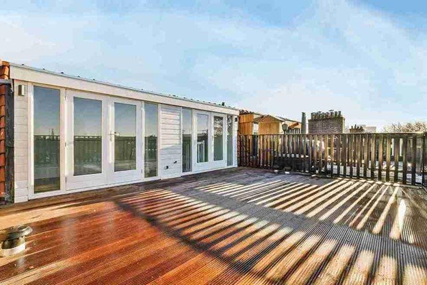 Large rooftop wood deck professionally built with railing and sliding doors, designed for outdoor living and durability.