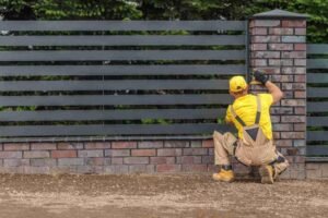 Fence installer reviewing measurements and plans near a residential property