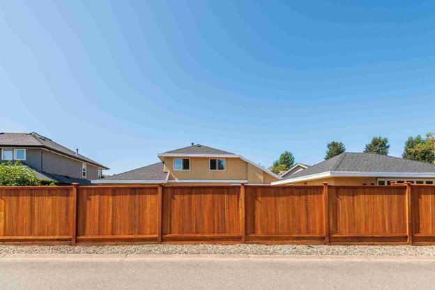 Person applying stain to a cedar fence for protection and long-term durability