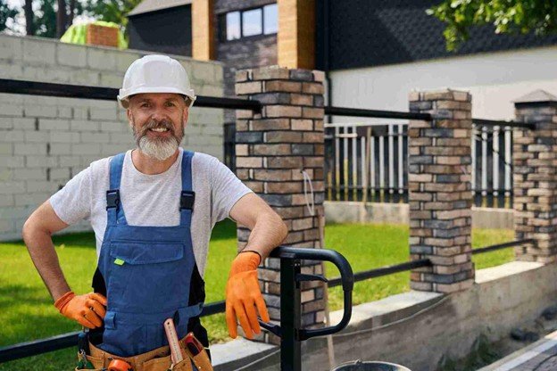 Professional fence contractor standing beside a completed residential fence