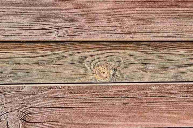 Close-up of weathered cedar boards with visible grain patterns, showing the texture and natural aging of wooden fence materials.
