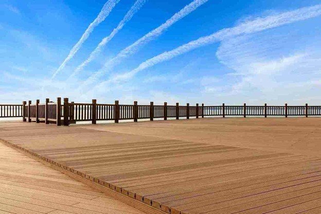 Large outdoor wood deck with railing overlooking an open landscape under a blue sky