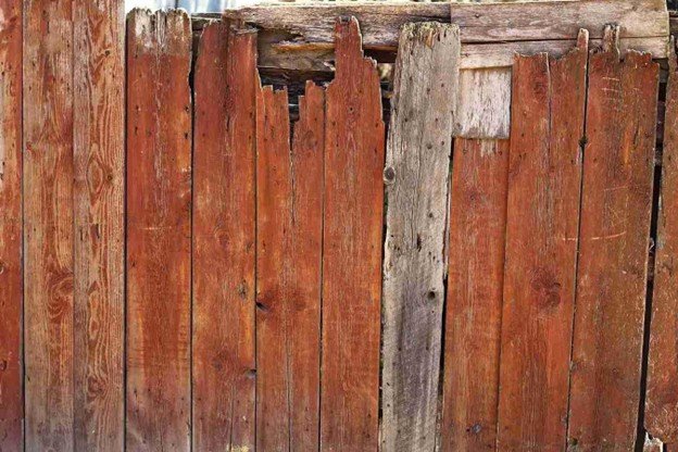 Old wooden fence with cracked and weathered boards showing visible wear and damage