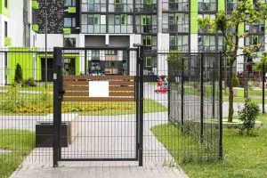 Black metal automatic gate installed at the entrance of a modern residential complex