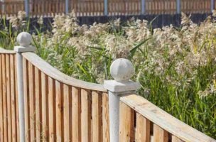 Wooden fence with concrete posts and round decorative caps on top