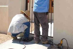 Technicians installing a new metal entry gate at a residential property